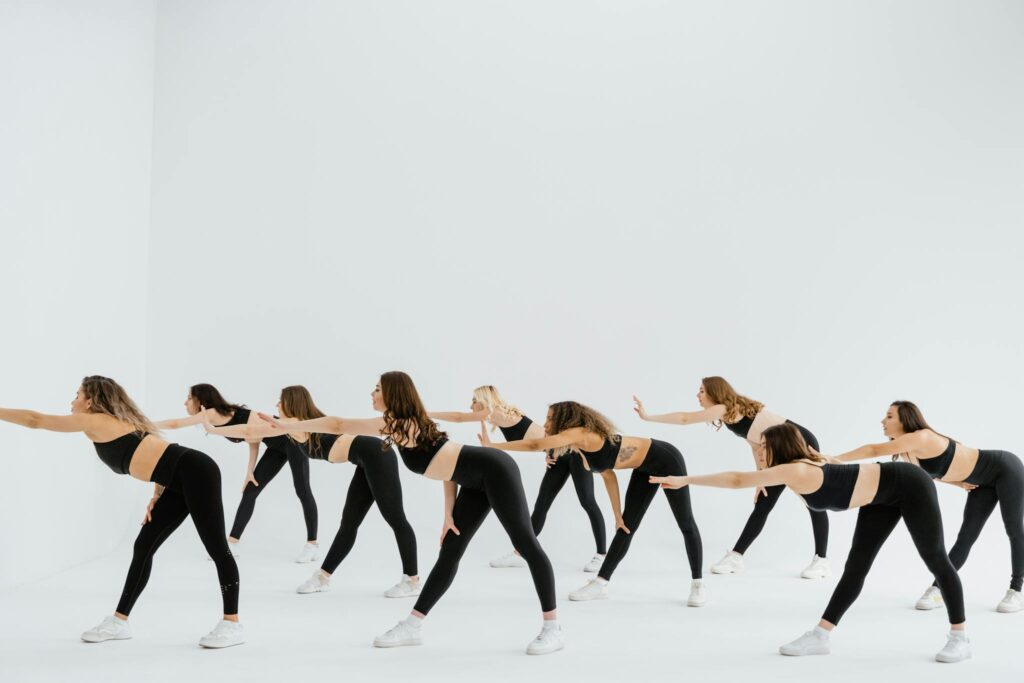 Women in activewear performing a group stretching exercise in a studio setting.